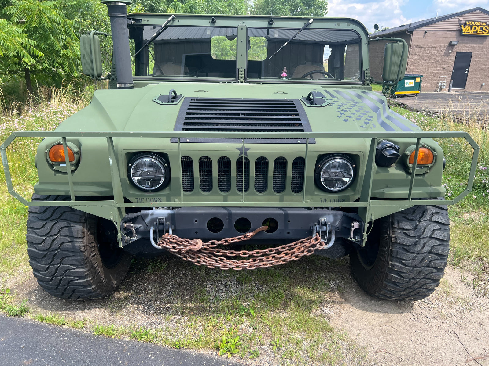 Olive green HMMWV head-on, recovery chains on the front lifting shackles