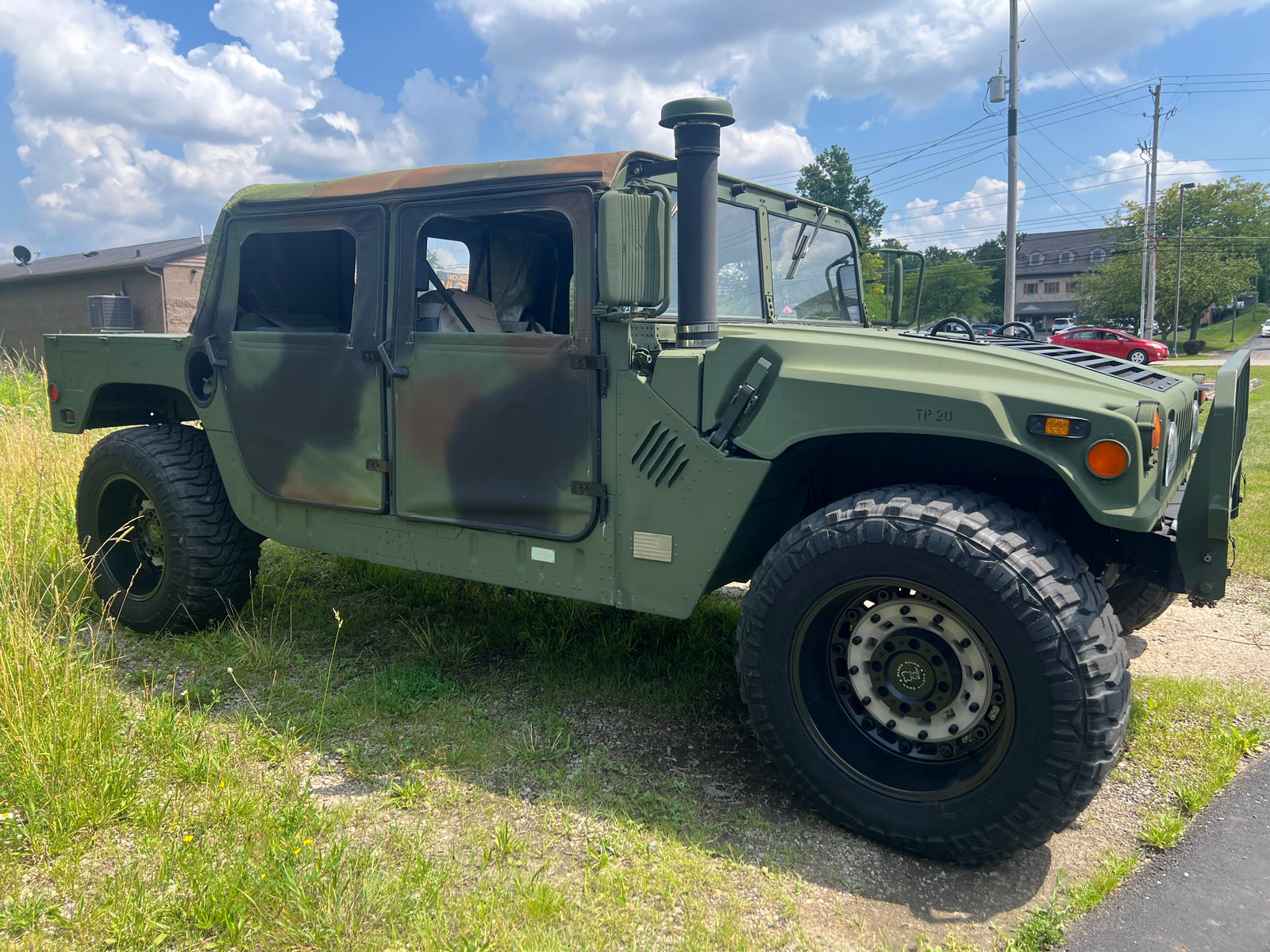 Olive green HMMWV in three-quarter view with the antenna mast up